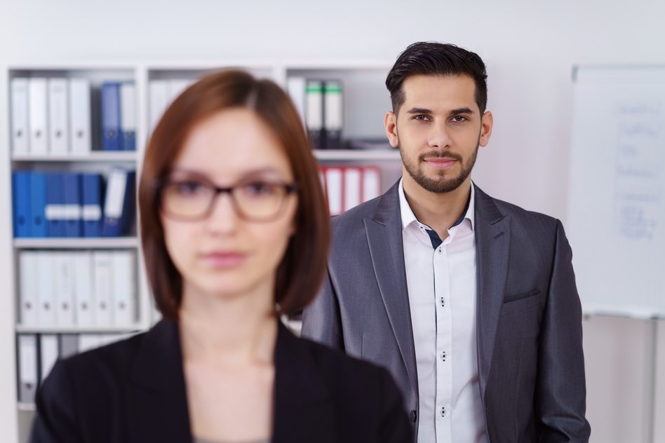 Calm businessman behind woman in office