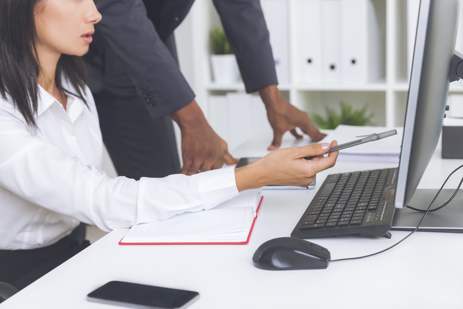 Close up of woman's hands showing a line of report at computer screen to her colleague. Concept of cooperation